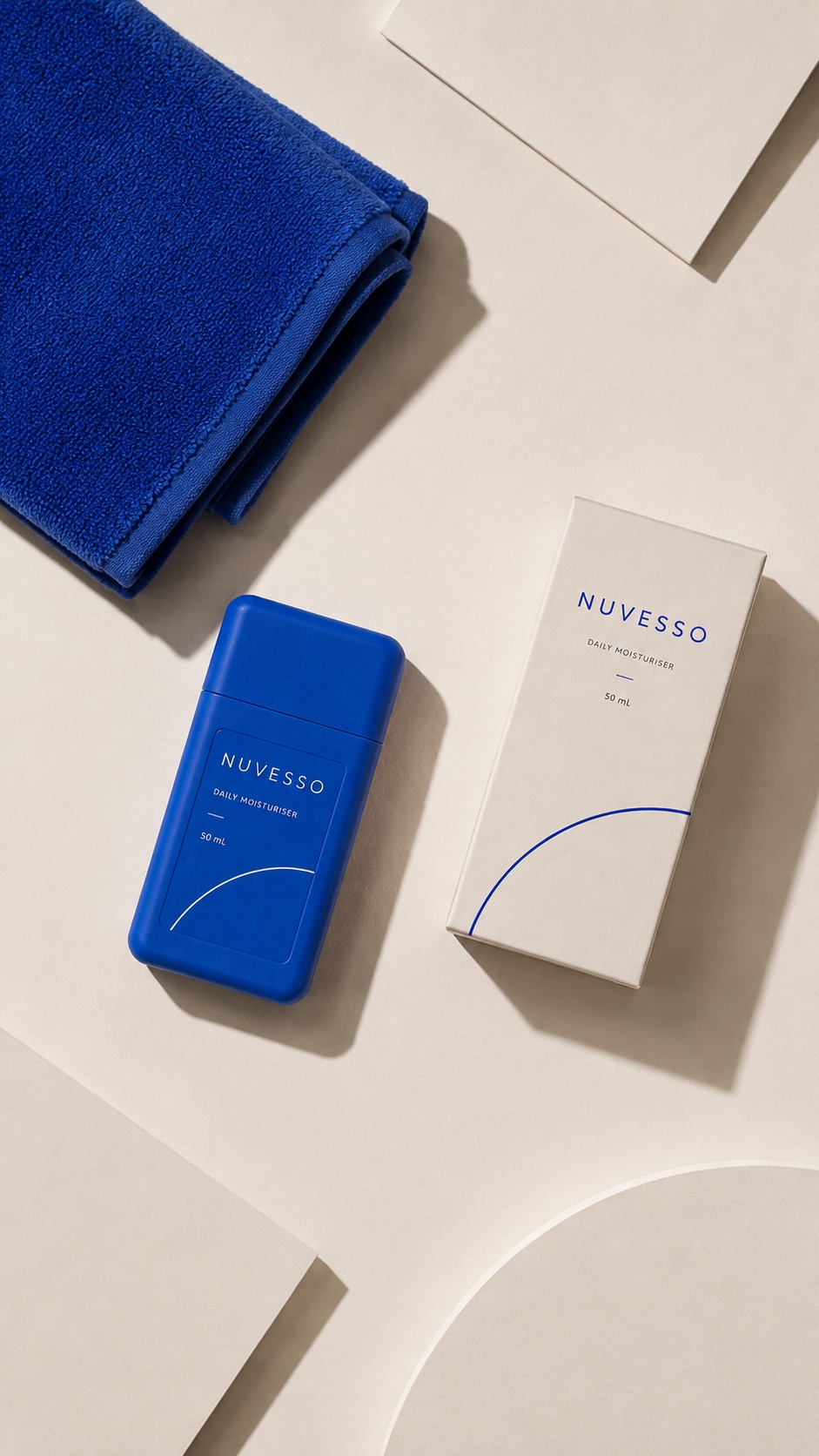 Overhead NUVESSO bottle, carton and cobalt towel on an ivory surface