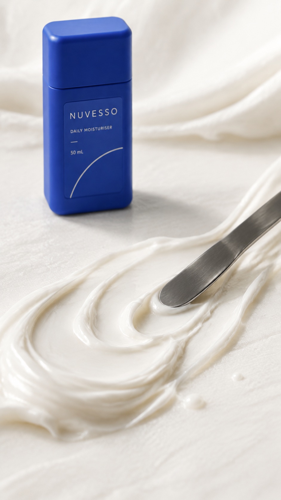 Macro ivory cream folds and a cosmetic spatula with NUVESSO beyond